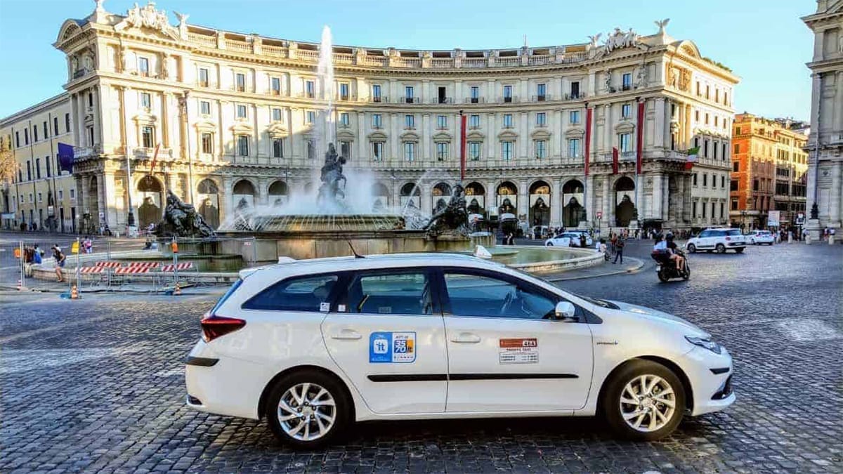white taxis parked around a large fountain in a paved square.