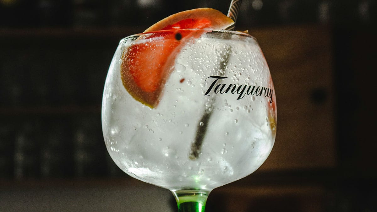 glass of gin and tonic garnished with a grapefruit wedge.