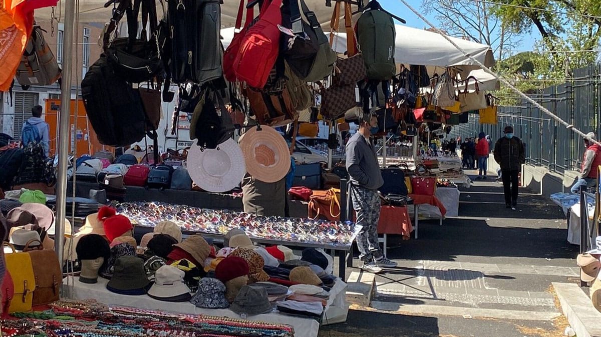 outdoor tables of hats, bags, and other accessories at a market.