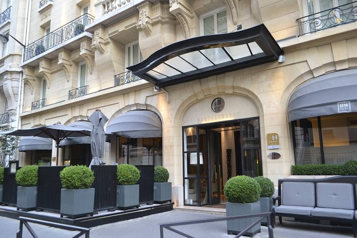 arched doorway into a hotel with black awnings over windows.