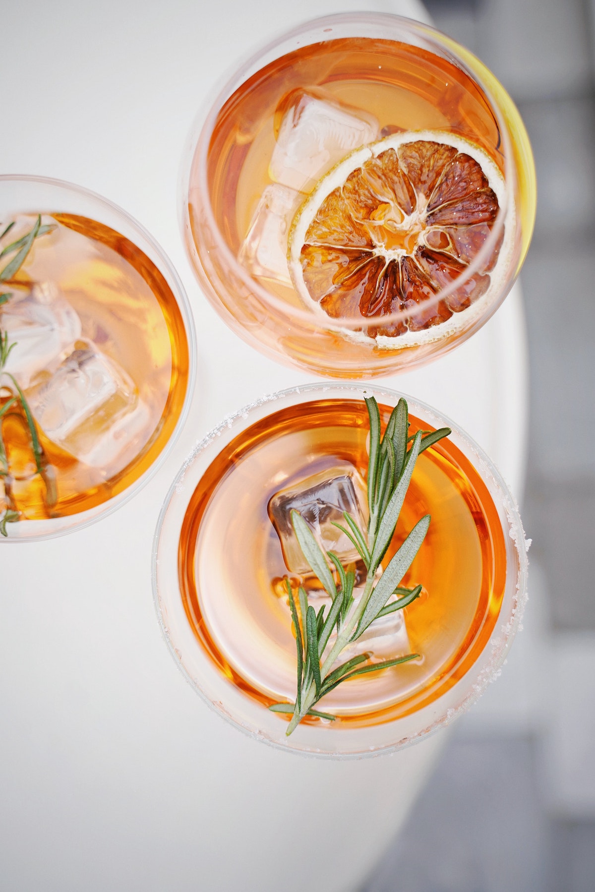 bird's eye view of three colorful cocktails on a white counter