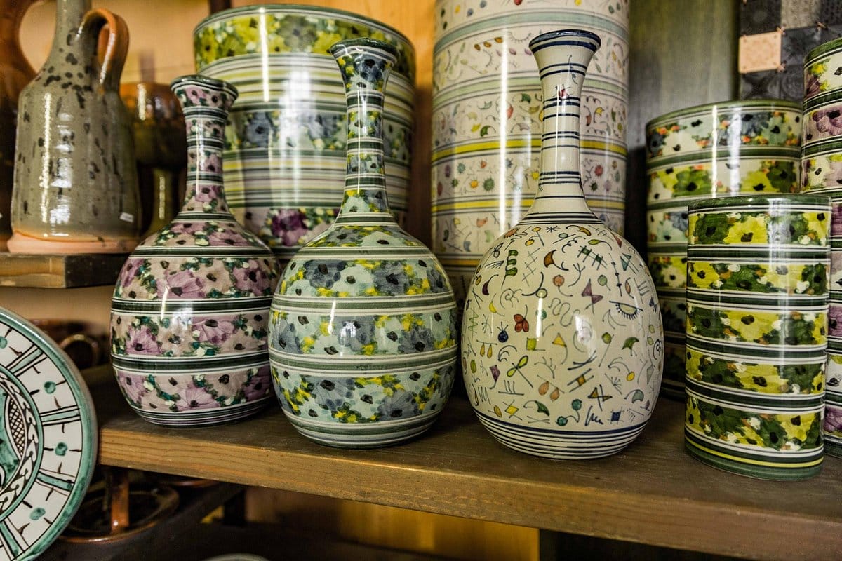 hand-painted ceramic vases on a wooden shelf in a gift shop.