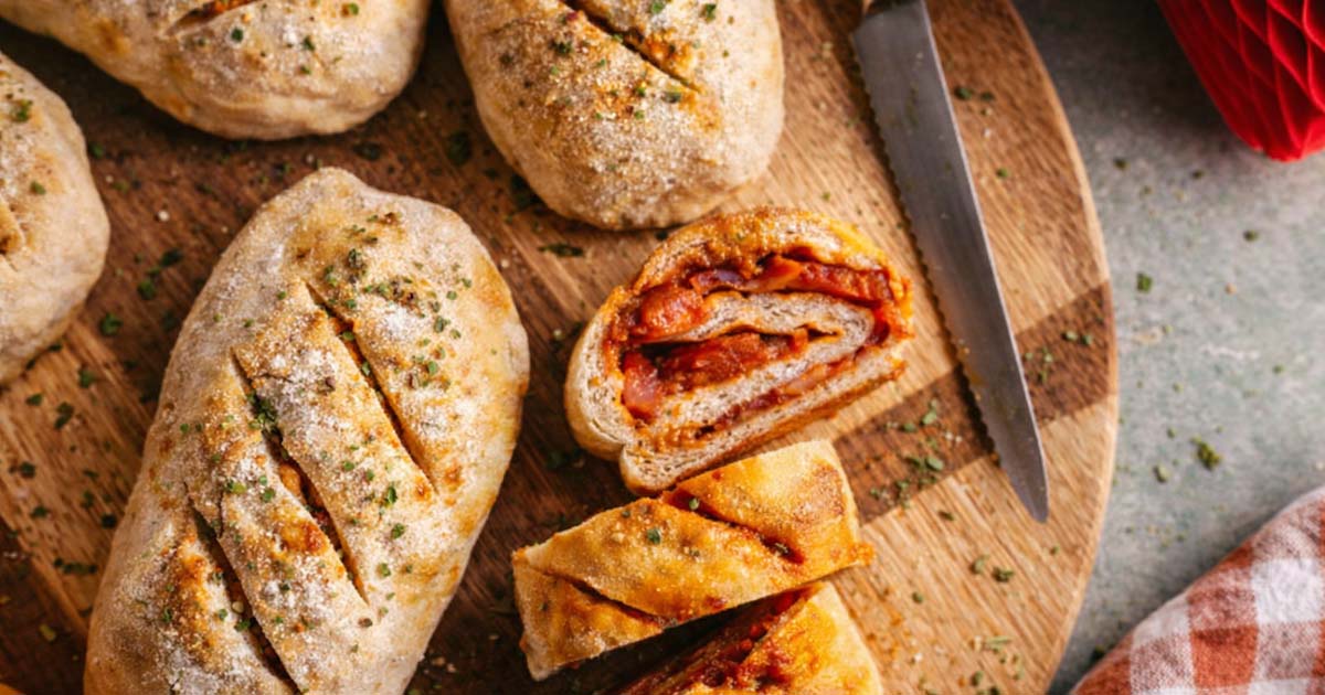 sliced bread filled with chorizo on a cutting board.