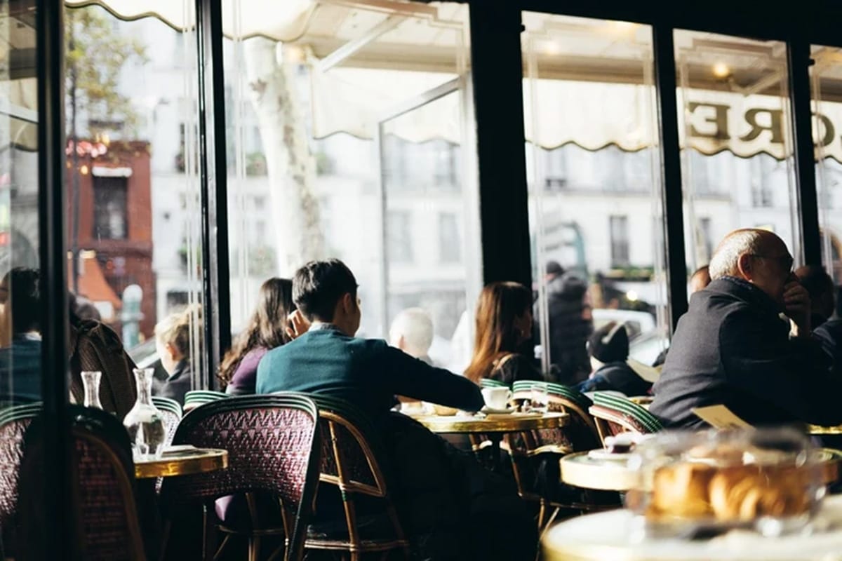 people seated at round tables in a Parisian cafe.