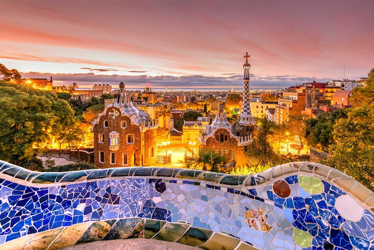 sunset over Parc Guell in Barcelona as seen from a mosaic-covered overlook.