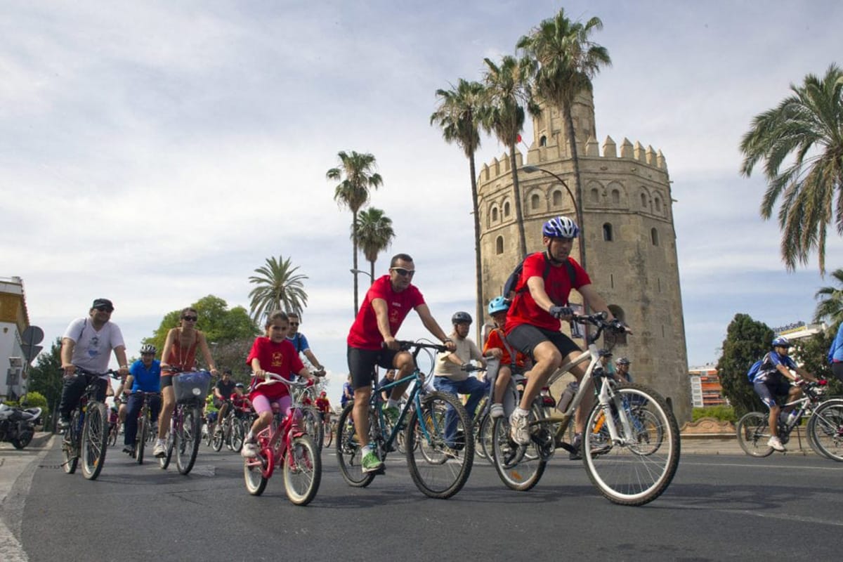 group of adults and children cycling through Seville on a road.