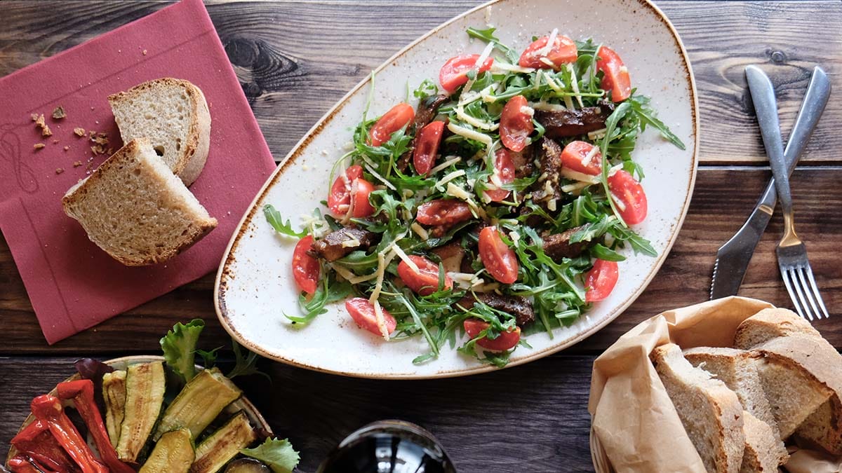 cooked veggies and a salad on plates on a wooden table.