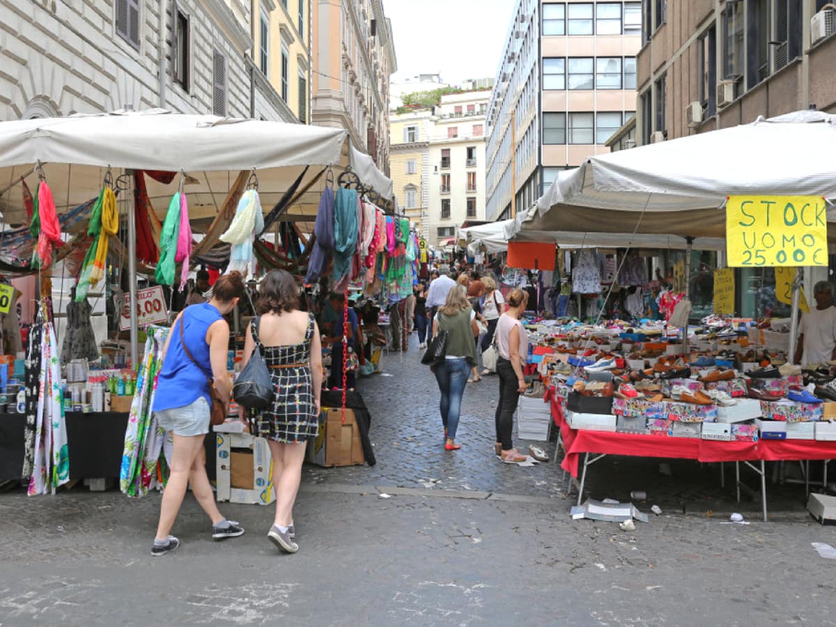 people exploring an outdoor flea market in Rome.