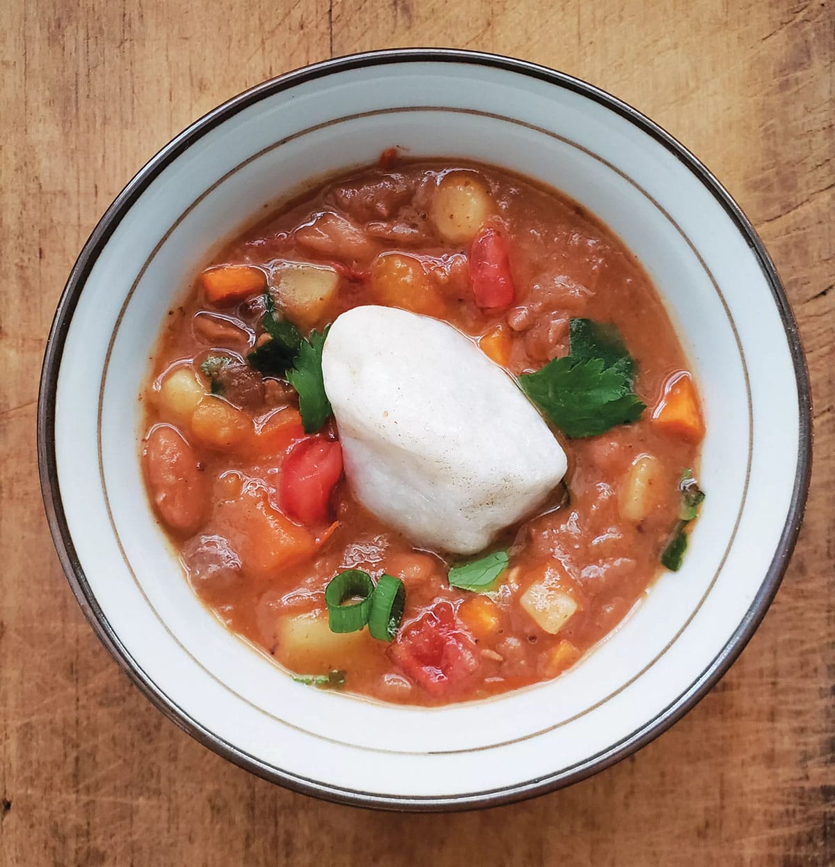white bowl of tomato-based vegetable soup with a large white rock in the center of the bowl.