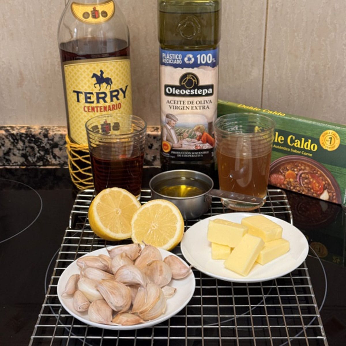 bottles of olive oil, whisky, and bowls of ingredients for Spanish whisky sauce.