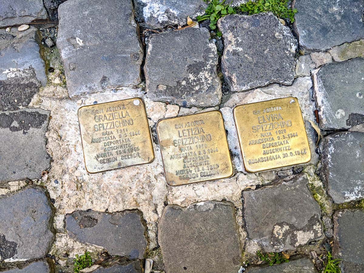 three gold-hued plaques in the midst of a cobblestone street in Rome.