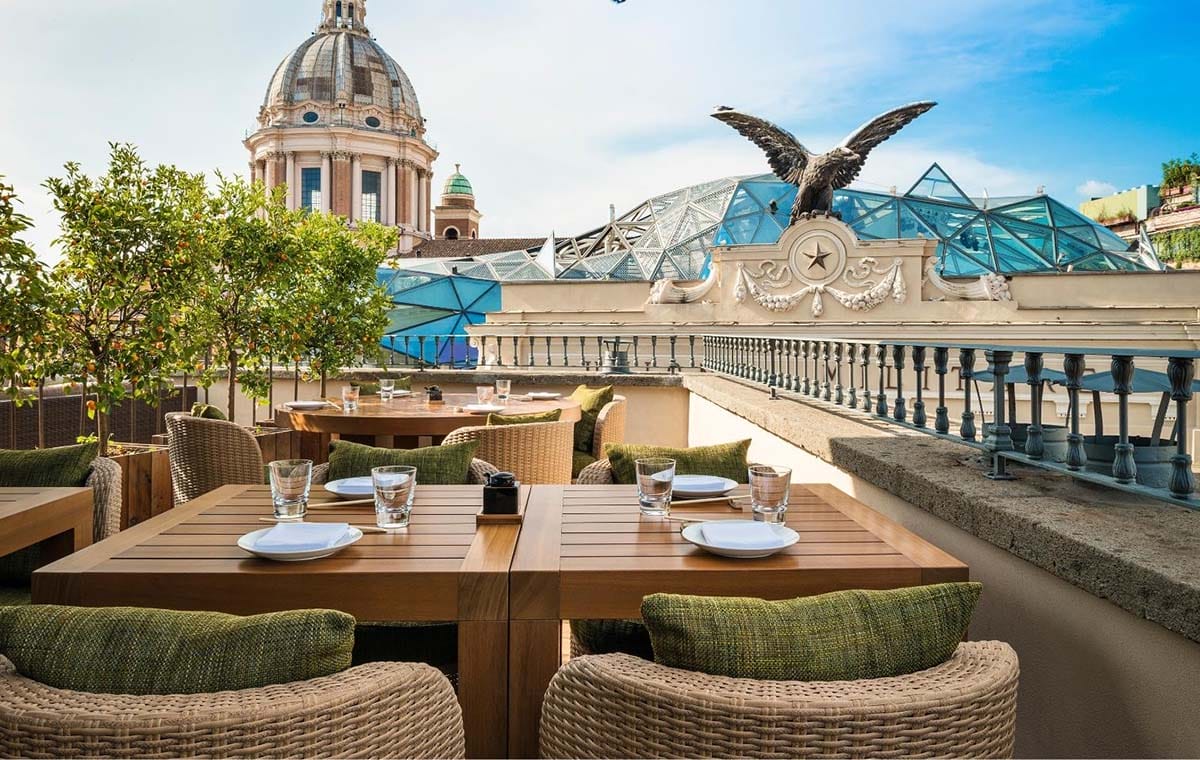 wooden table and wicker chairs on a rooftop terrace in Rome.